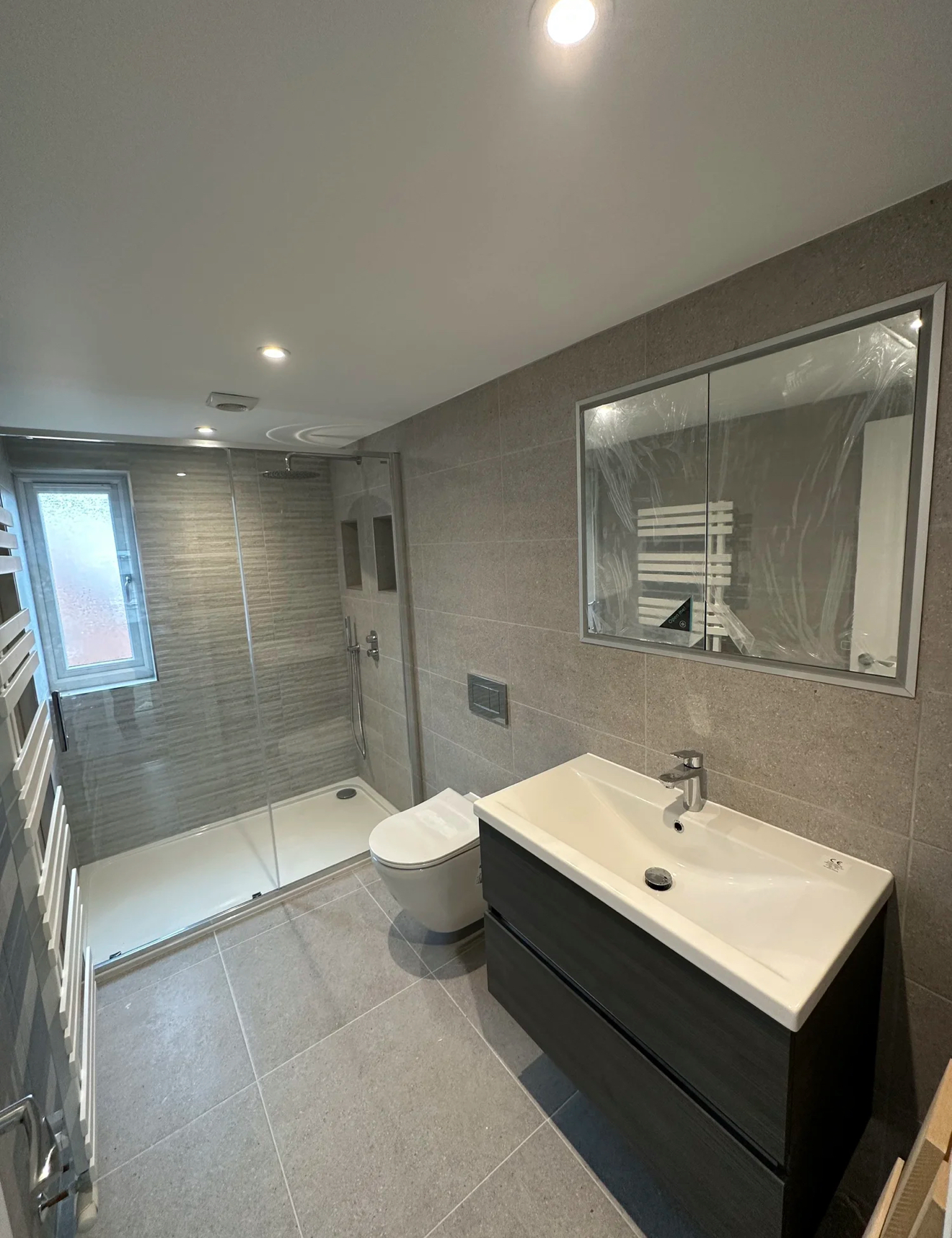 Contemporary grey shower room with floating vanity and large mirror — bathroom installation Haslemere